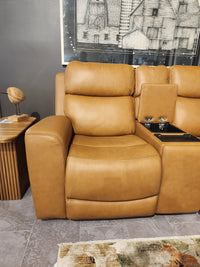 Denver 2 Power Recliner Loveseat by 16 WEST with lumbar support and cup holder, beside a table and wall art.