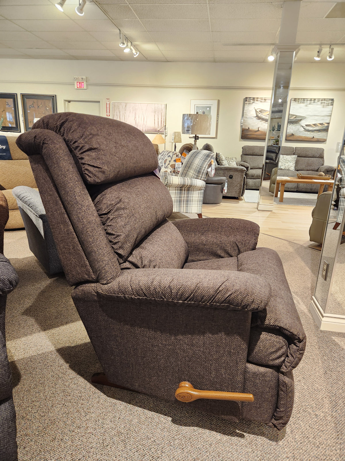 La-z-boy 519 Astor Rocker Recliner with brown upholstery and wooden lever, displayed in a furniture showroom.