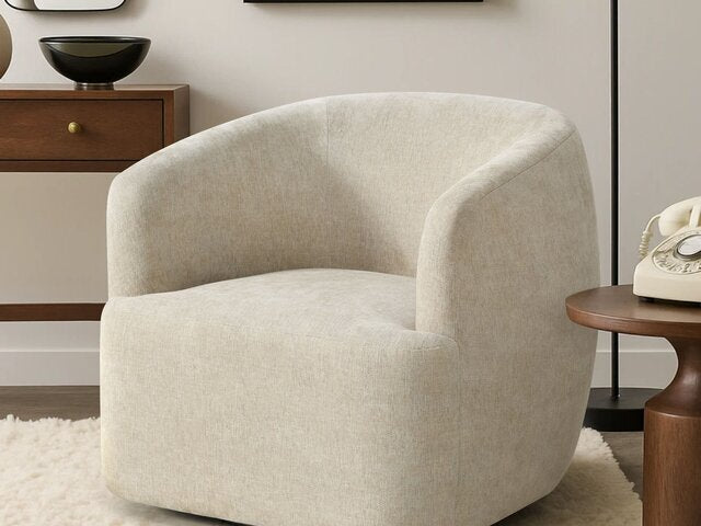 The B6515 Sofia Swivel Chair by Donald Choi sits on a white rug next to a wooden side table and vintage telephone.