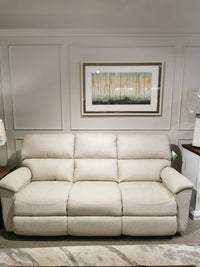 A beige La-Z-Boy 727 Brooks Reclining Sofa sits against a white wall with framed art above and a rug below.