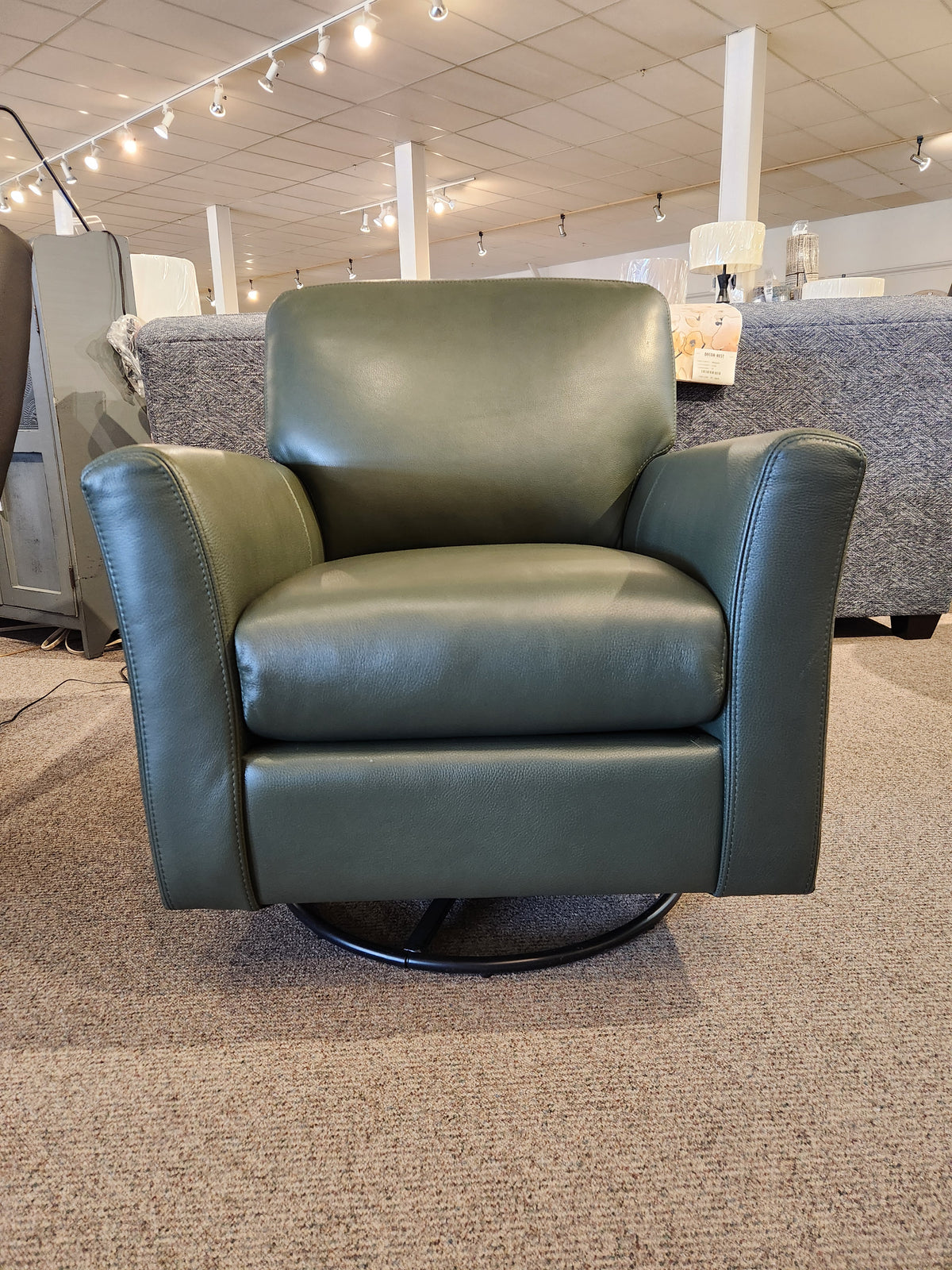 The Leather Craft 745 Leather Swivel Rocker Chair in green is handmade in Toronto and displayed on our carpeted showroom floor.