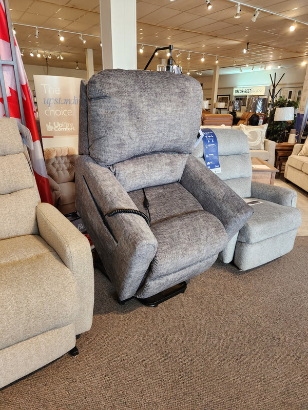 The La-z-boy 793 Jean Bronze Lift Chair is showcased in a showroom, surrounded by other recliners.