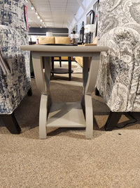 The Durham 900-532 Transitional Chairside End Table with curved legs sits between two armchairs on a carpeted floor.