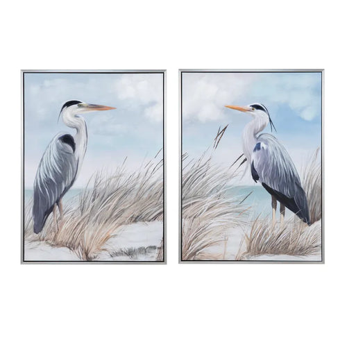 The Twin Beaks Framed Canvas by Crestview Collection features blue herons among seagrass under a cloudy sky.