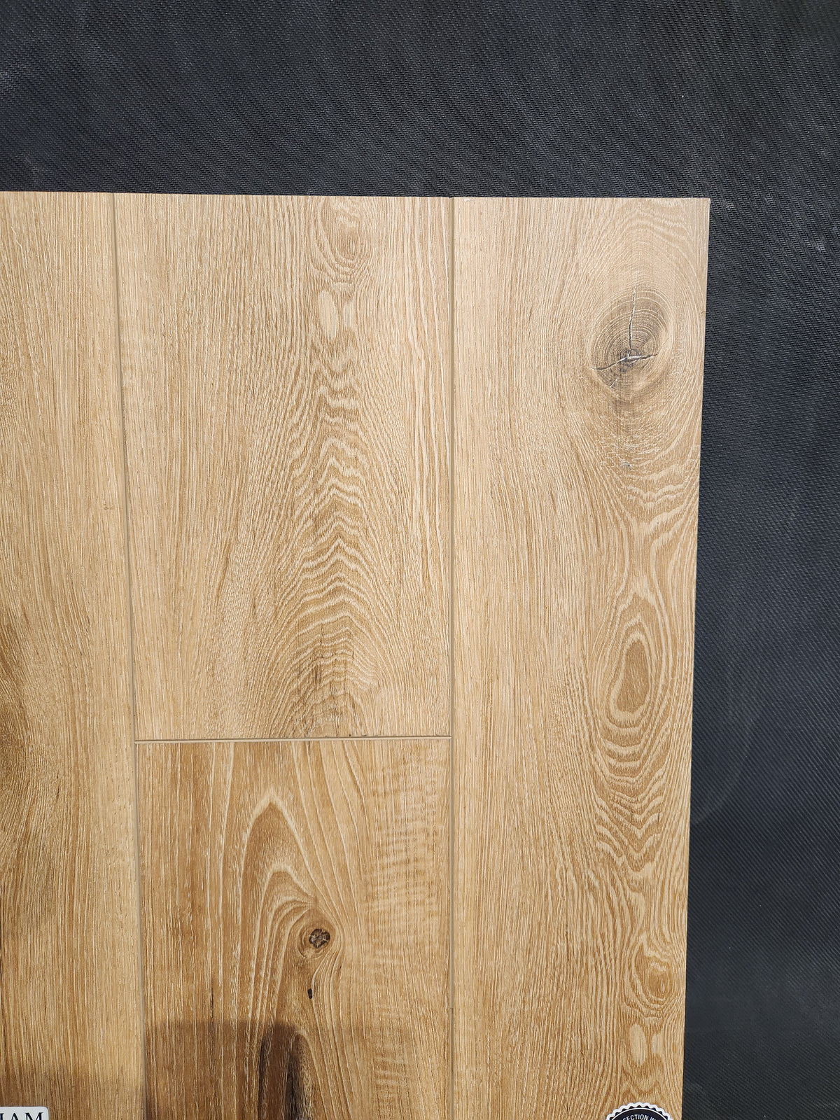 Little Ben XL Luxury Vinyl (Click Plank) by Beckham Brothers, light brown wood grain, shown on a dark textured background.