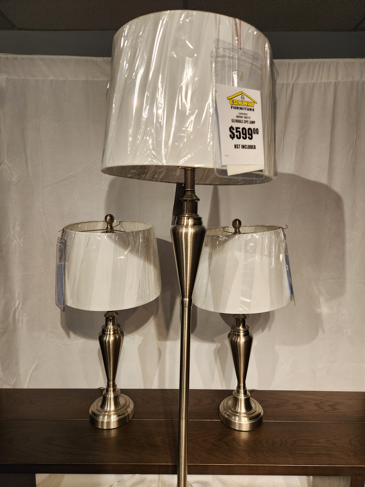 The Adesso Lamp Glendale 3 Piece Lamp Set features brushed metal lamps and a floor lamp on a wooden surface.