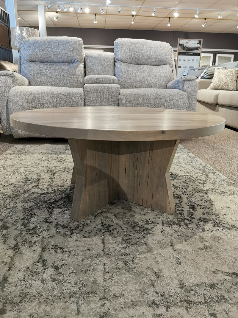 Handstone JA36R Jasper 36" Round Coffee Table with star base, shown on a rug among sofas in the showroom.