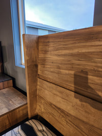Close-up of the Handstone JA-QW Jasper Queen Platform Bed headboard by a window, sunlight streaming in.