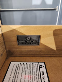 A metal Handstone label from the Jasper Collection is on wood above a warning label inside a JA18 6 Drawer Dresser.