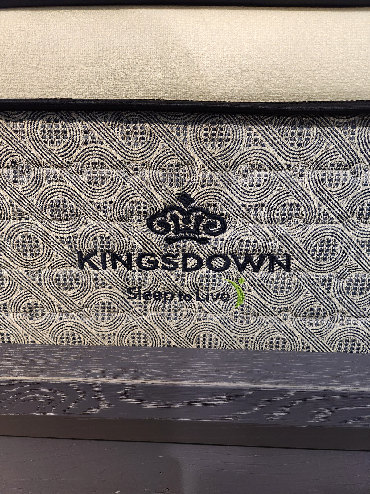 Close-up of a KingsDown Radiance Elite 2 ET Firm Mattress label with patterned, cooling comfort fabric.