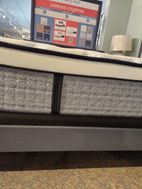 The KingsDown Radiance Elite 2 ET Firm Mattress offers cooling comfort on a gray, patterned bed frame in-store.