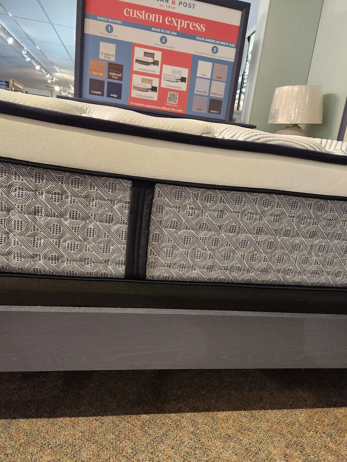 The KingsDown Radiance Elite 2 ET Firm Mattress offers cooling comfort on a gray, patterned bed frame in-store.