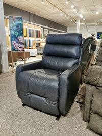 The Kristisha 9NZ31LV Power Lift Chair by Best, in dark gray leather, is showcased on a carpeted showroom floor.