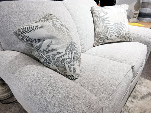 A light gray 899 Duo Bennett Loveseat from La-Z-Boy® with fern cushions sits in a well-lit room.