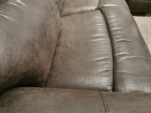 Close-up of La-Z-Boy's 521 James Loveseat, a grey leather recliner with stitching and contoured seats under soft lighting.