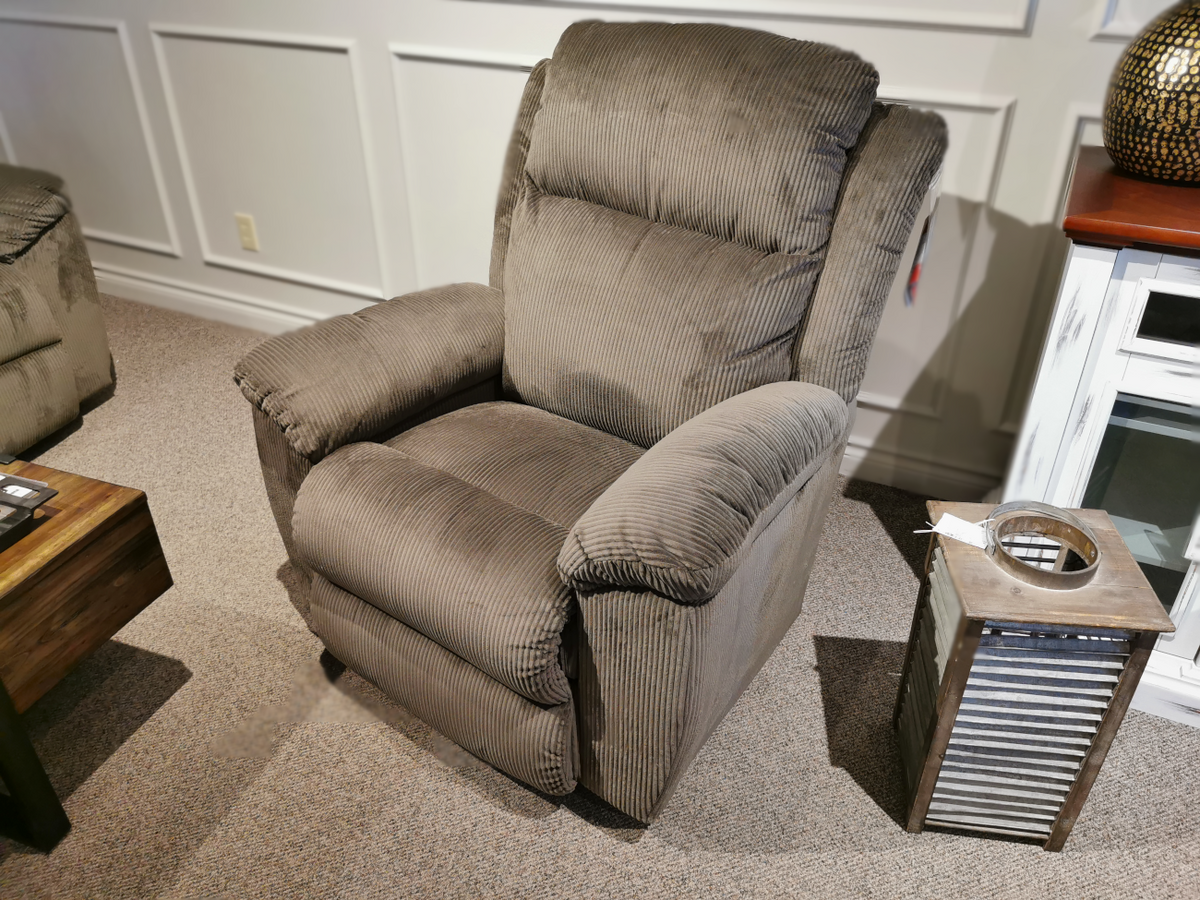 A La-z-boy 761 Joel Reclining Chair with cushioned arms sits by a rustic table in a paneled, carpeted room.