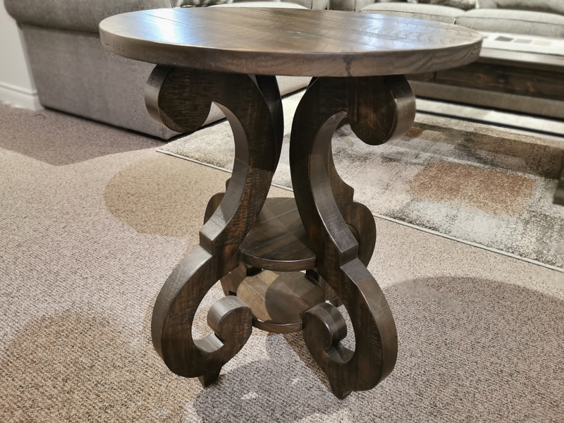 Magnussen's 2491 Bellamy Round Accent Table with a carved base, adds rustic charm to a cozy carpeted living room.