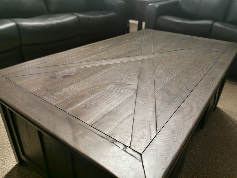 The Magnussen 3778 Garrett Cocktail Table features dark wood with a geometric pattern, complementing black leather sofas.