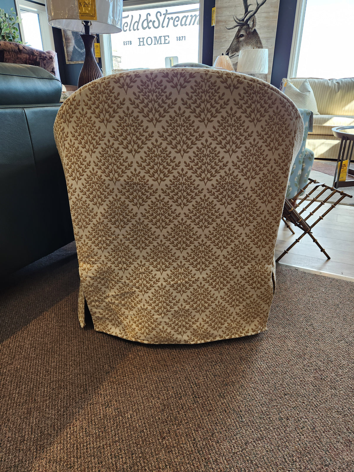 The Meg Swivel Chair by Best, with a repeating leaf pattern, sits on a brown carpet in a sunlit room.
