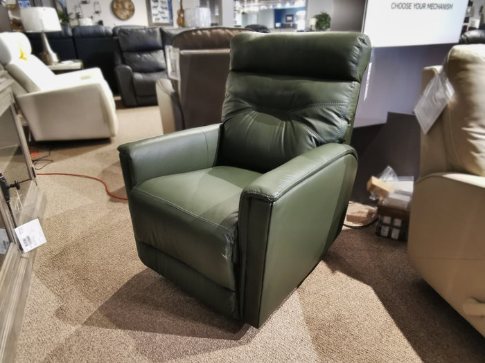 A green Palliser 43003 Denali Swivel Power Glider sits on a beige carpet amid living room furniture in a showroom.