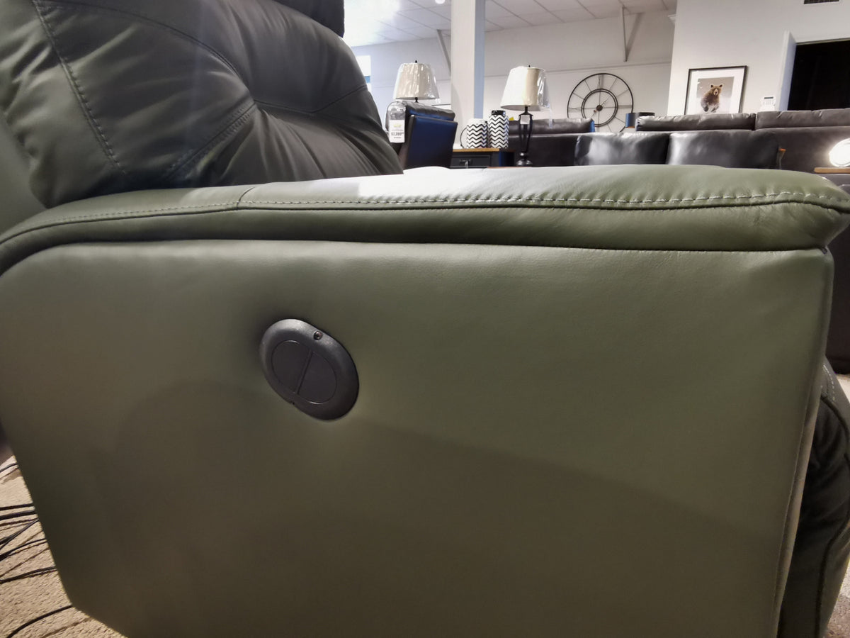 Close-up of a green Palliser 43003 Denali Swivel Power Glider's side with a round adjustment button in a showroom.