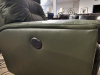 Close-up of a green Palliser 43003 Denali Swivel Power Glider's side with a round adjustment button in a showroom.
