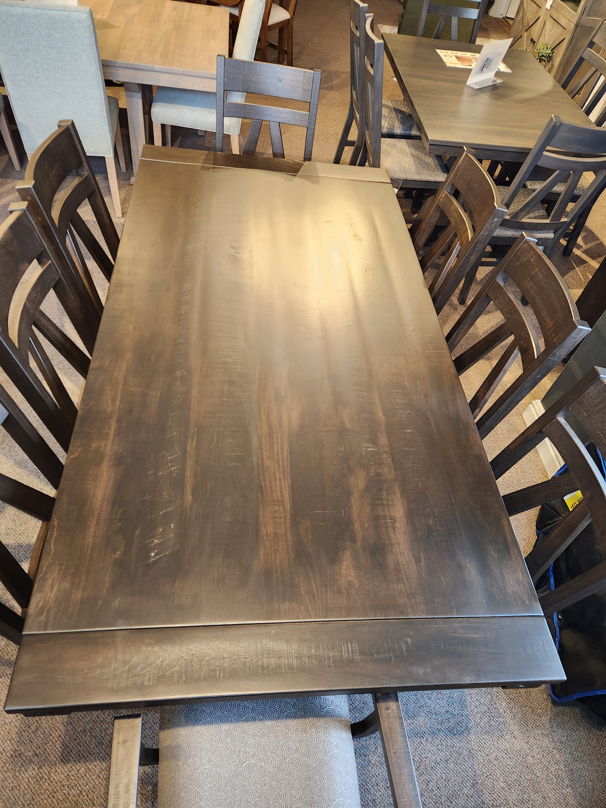 The RA4284 Rafters Dining Package by Handstone features a large wooden table with rustic chairs in a showroom setting.