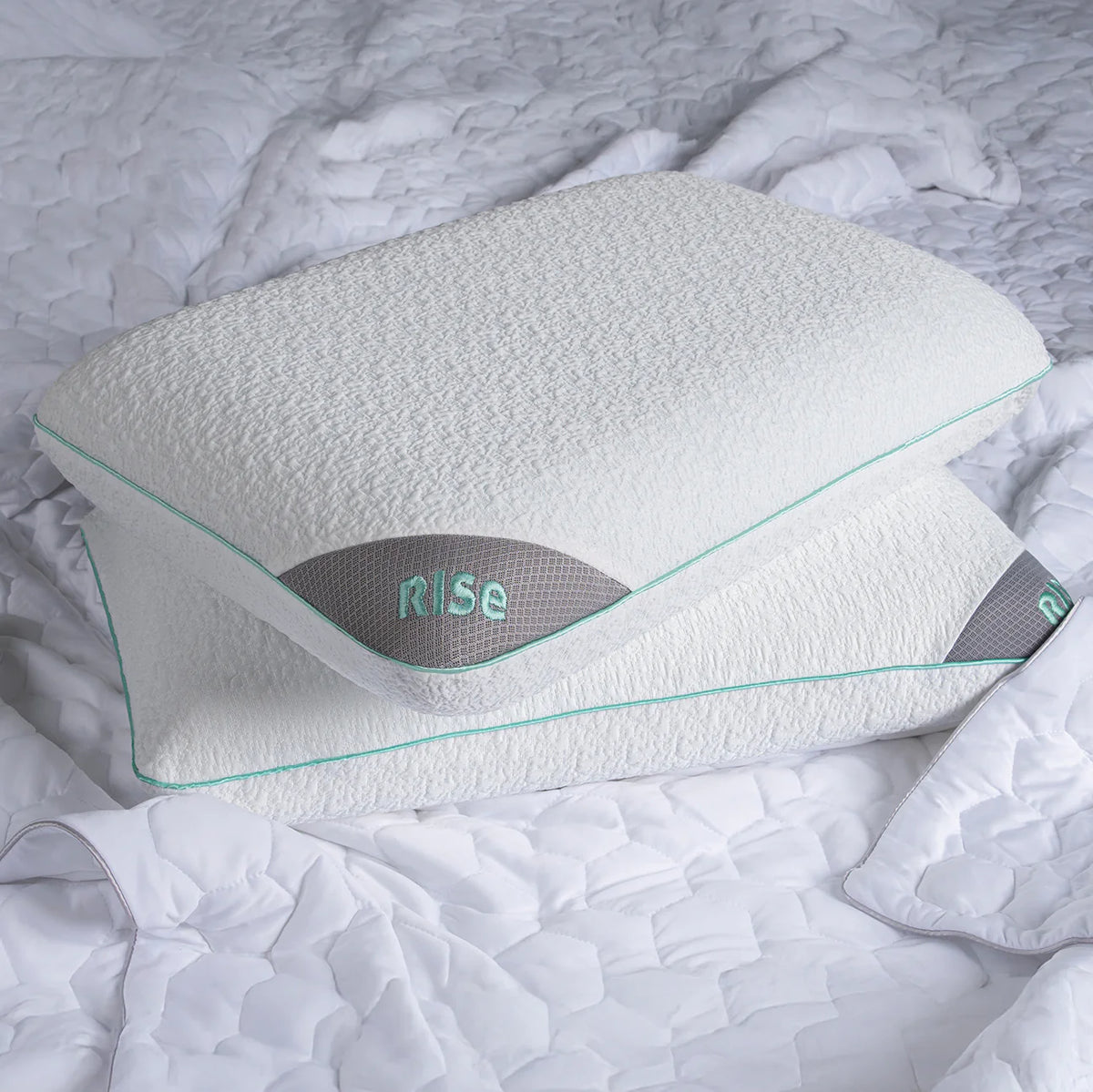 Two white Bed Gear Rise Performance Pillows stacked on a white quilted bedspread.