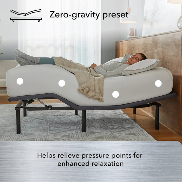 A woman relaxes on the Beauty-Rest Silver Adjustable Base in zero-gravity mode with pressure relief zones and wireless remote.