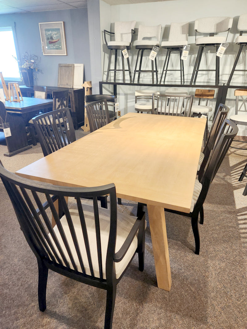 The Universal Modern Farmhouse Miller Dining Table Package with six black chairs, displayed in a showroom.