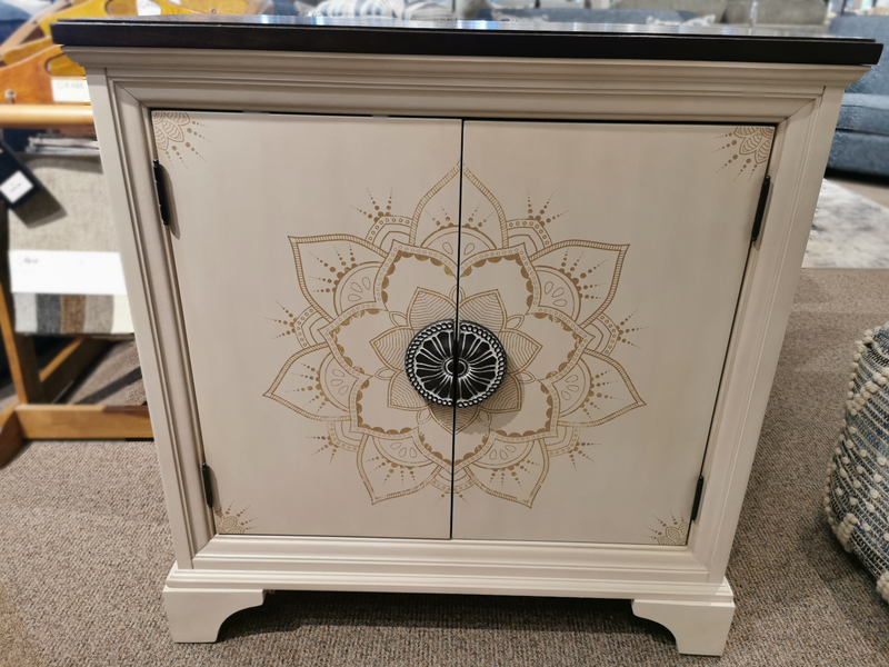 Universal M20636964 Accent Console with faux hand-painted mandala motif and round knob on a carpeted floor.