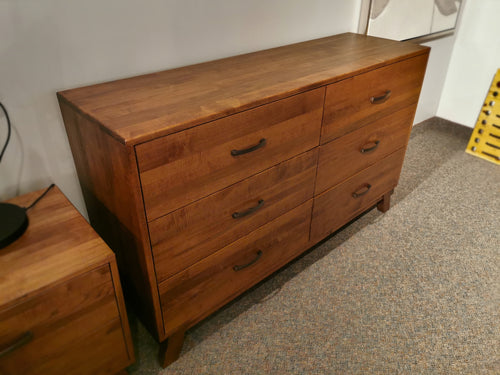The Vokes Rocklynd Dresser, with six drawers and metal handles, adds a modern touch to the carpeted room.