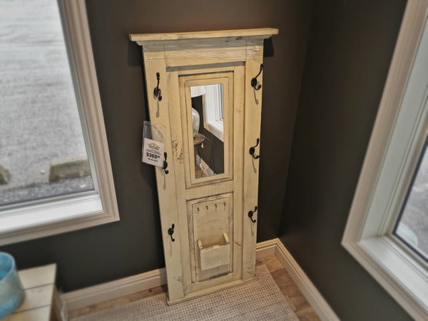 The 710 Doorganizer by Woodcraft, a handmade wooden wall-mounted unit with hooks and a small shelf, crafted with exquisite techniques, stands in a corner between two windows, adding a touch of Ontario charm to your home.
