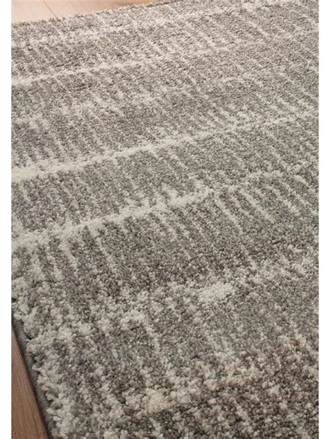 A close-up of the Kalora Sable 6901/G240 grey machine-made rug with a subtle linear pattern on wood flooring.