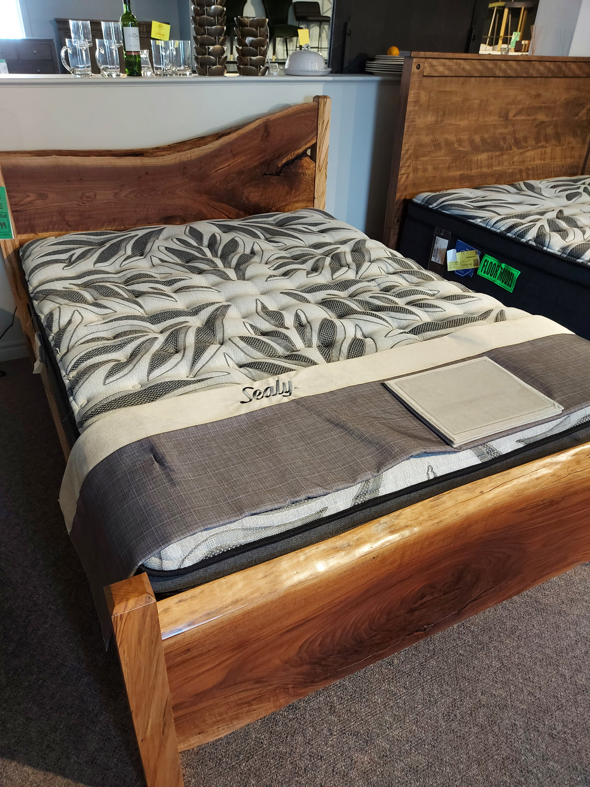 A wooden bed frame with a Sealy Sunset Vista Mattress featuring a euro pillow top and patterned leaf-design cover.
