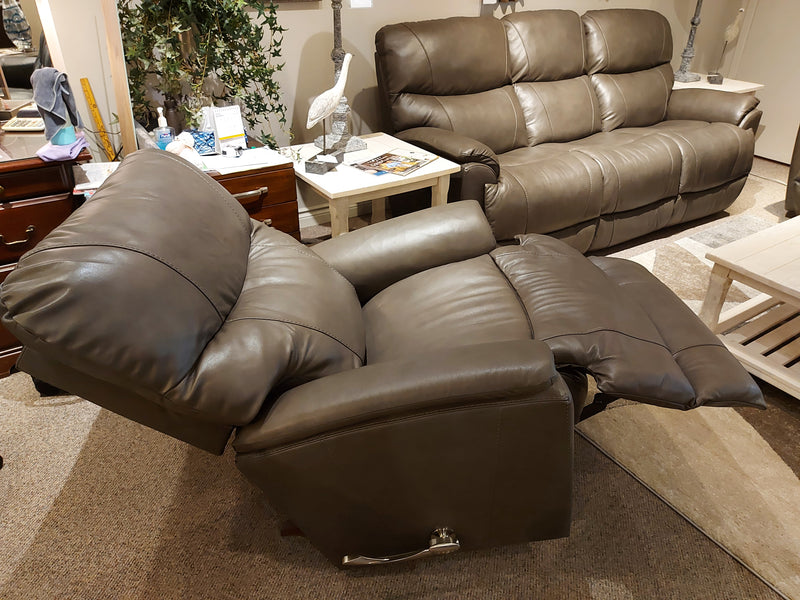 A 724 Trouper Leather Recliner by La-Z-Boy in gray is displayed with a sofa and other contemporary furniture.