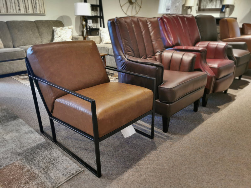 A row of five unique armchairs, featuring the Decor-rest 3071 Chair in brown leather, crimson leather, and tan leather designs, captures mid-century design flair and Hollywood glamour on a carpeted showroom floor.