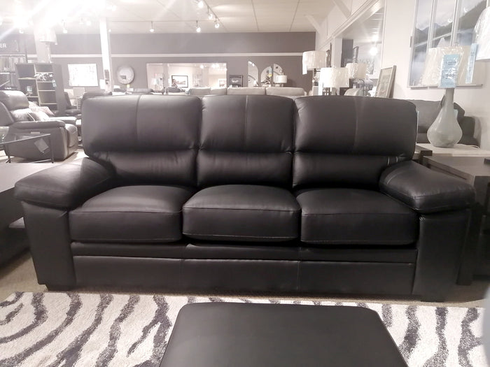 The Colorado Leather Sofa by Leather Craft is displayed in-store with decor and a zebra-patterned rug.