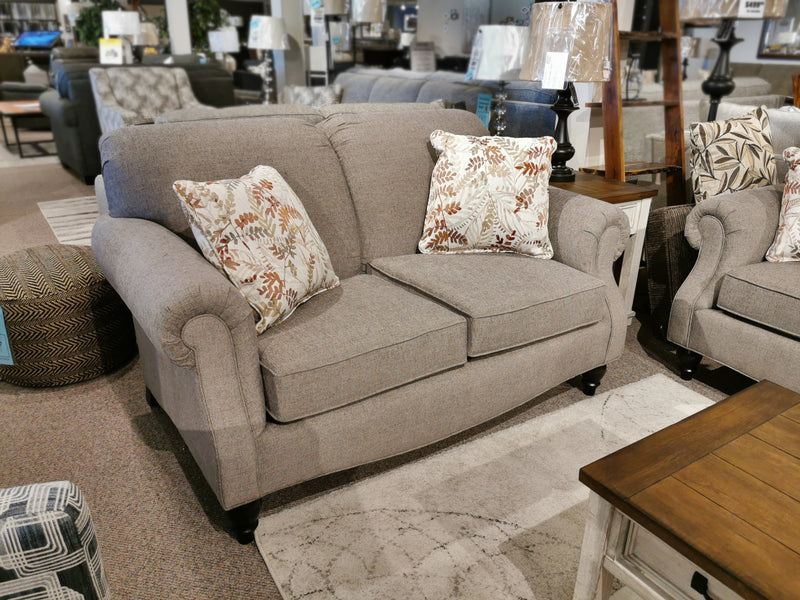 The Superstyle 7303 Loveseat, a gray polyester Canadian sofa with two patterned cushions, is on display in the showroom.