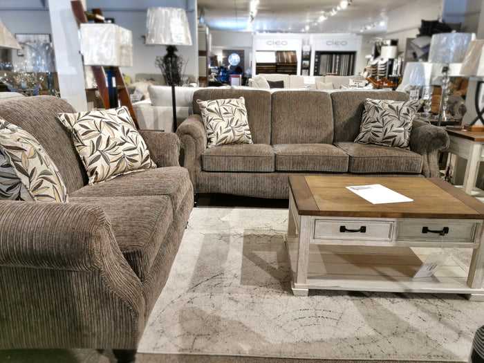 Living room with two Superstyle 7303 sofas, leaf pillows, wooden table, and lamps in a showroom.