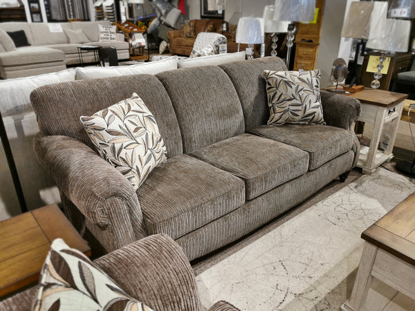 The Superstyle 7303 Sofa, a Canadian piece with rolled arms, is presented with two patterned cushions and wooden side tables.