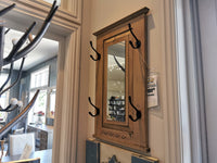 The Woodcraft 712 Doorganizer, priced at $199.99, is a vintage grey stained wooden wall-mounted mirror complete with a shelf and hooks. Ideal for enhancing any room's charm, it offers a practical 2-D space storage solution. On display in a furniture store, this piece combines style and functionality to enhance your daily organization needs.