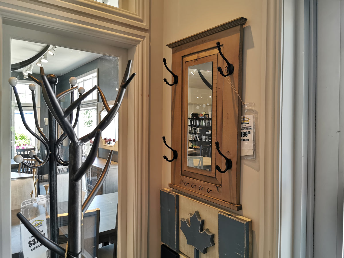 In the store, Woodcraft's 712 Doorganizer is elegantly displayed. This wooden wall-mounted mirror with coat hooks features a vintage grey stain and is priced at $199.99. Alongside it, a partially visible coat rack offers smart 2-D space storage solutions while complementing the functional and stylish design of this piece.